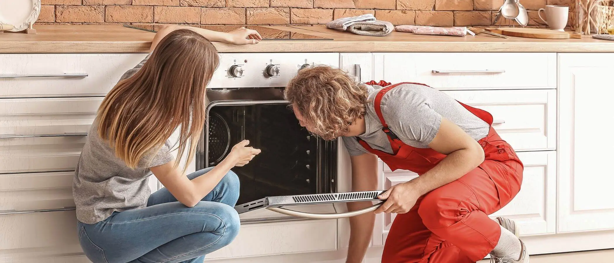 Clean and Maintain Your Oven for Longevity Young Repairman Repairing Refrigerator In Front Of Woman